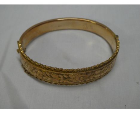 A 9ct gold oval bangle with engraved decoration, cased