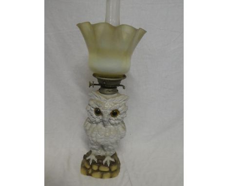 A Continental china oil lamp in the form of an owl with metal mounts and opaline shade, 21" high overall