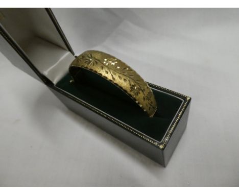 A 9ct gold circular bangle with engraved floral decoration, cased 