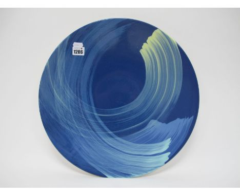 A Poole Studio Pottery Charge, with cream swirl decoration on blue ground, 41cm diameter monogrammed 'CM'.