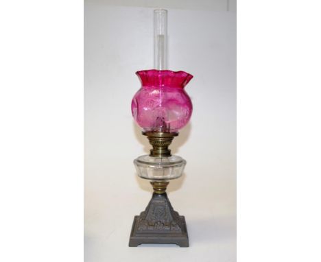 Early iron based fuel banquet lamp moulded iron base, to clear glass fuel reservoir, with brass burner, to etched red glass s