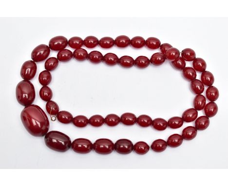 A GRADUATING BAKELITE BEAD NECKLACE, oval cherry amber colour beads, graduating in size, largest measuring approximately leng