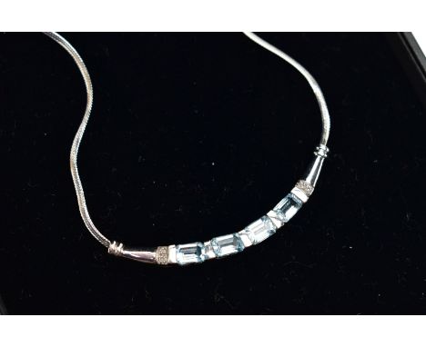 A 9CT GOLD, TOPAZ NECKLACE, a solid white gold crecent shaped bar, set with four emerald cut blue topaz stones, accented with