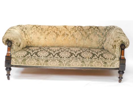 A Victorian Aesthetic movement ebonised and parcel gilt Chesterfield sofa, with a buttoned back, upholstered in green pattern