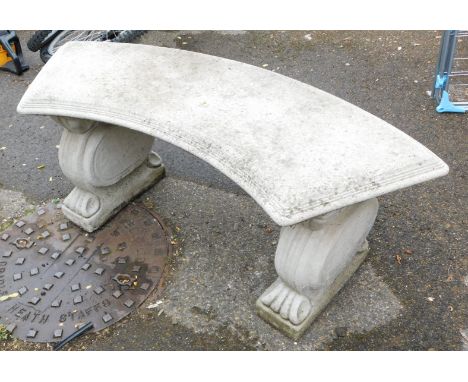 A reconstituted stone curved garden bench, raised on scroll ends supports.