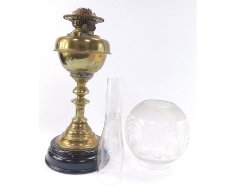 An early 20thC brass oil lamp, raised on a turned black socle, with chimney and etched globular glass shade, 67cm high.