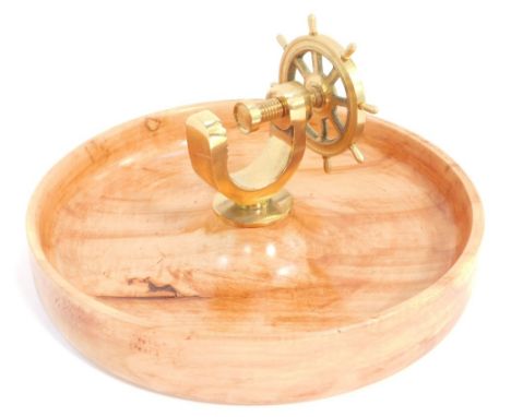 A novelty brass capstan wheel nut cracker, mounted on a walnut bowl, 26cm wide.