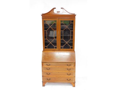 An Edwardian mahogany and satinwood banded bureau bookcase, the break arch pediment over a pair of glazed doors enclosing thr
