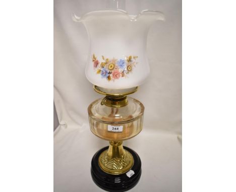 A late 19th/ early 20th century oil lamp having glass reservoir and floral shade.