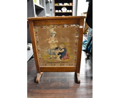 A Victorian fire screen having embroidered picture of Martha Morphet's work 1859 with oak surround