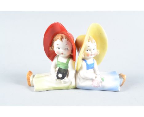 German Goebel Bookend Fairings of Photographic Interest,  seated small girls back to back, one in red hat with camera, the ot