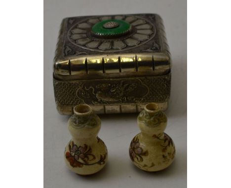 An Oriental white metal lidded box, with embossed dragon motifs, the lid inset jade roundel, 7cm square, containing a pair of