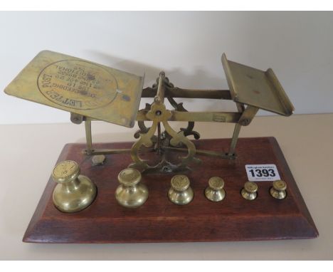 A late Georgian/Victorian set of brass postal scales with 6 bell weights from 1/2 oz to 8 oz - set on a walnut base 