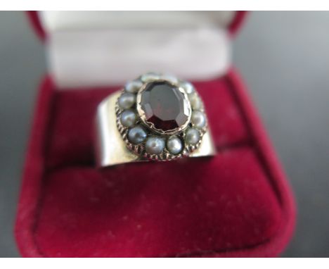 An attractive Georgian rose gold ring set with an oval garnet measuring 8mm x 6mm - surrounded by 12 seed pearls - gold teste