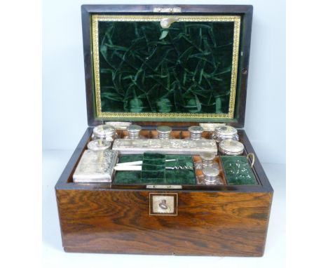 A Victorian dressing table box with silver topped glass bottles and jars, lacking some veneer 