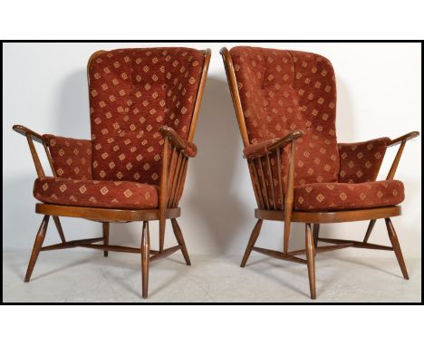 A pair of vintage retro 20th century Ercol beech and elm wing back spindle back armchairs raised on tapered supports with red