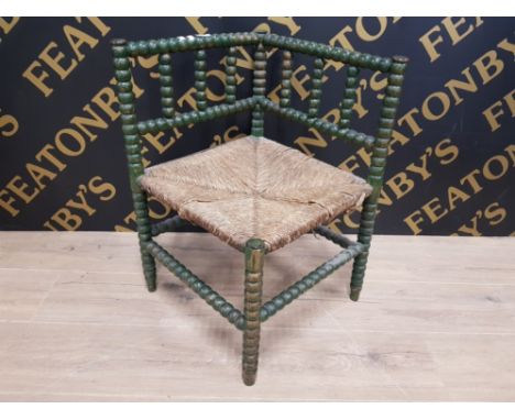 A LATE 19TH EARLY 20TH CENTURY GREEN PAINTED BOBBIN TURNED CORNER CHAIR WITH RUSH SEAT