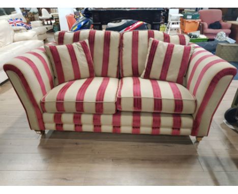 A BARKER AND STONEHOUSE TWO SEATER SOFA RAISED ON BRASS CASTORS TOGETHER WITH A LOOSE FITTING PROTECTIVE COVER