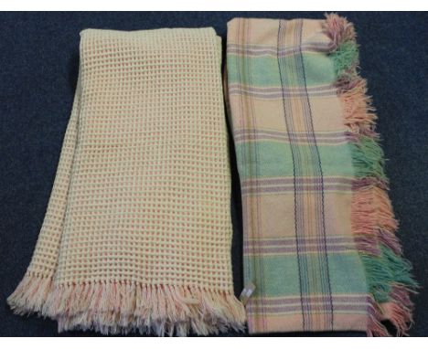 Two vintage blankets, one a pink and cream honeycomb blanket, the other a fringed green and pink checked blanket. (2)(B.P. 24
