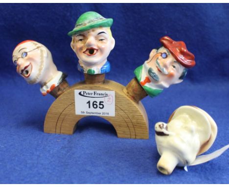 Set of four ceramic novelty painted wine bottle stoppers in the form of heads, on stand.(B.P. 24% incl. VAT)