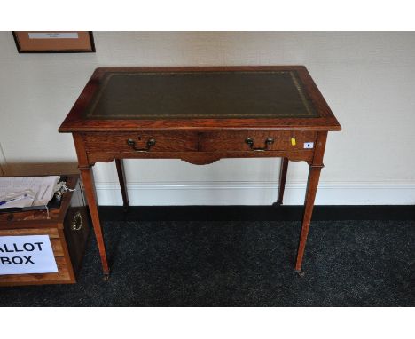 AN EDWARDIAN TWO DRAWER WRITING TABLE, with embossed green leather insert standing on square tapered legs terminated with bra