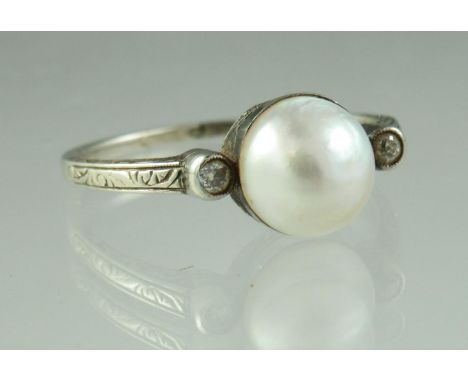 An early 20th century pearl and diamond ring set in engraved white metal with an engraved band. Ring size O. Approx weight 2.