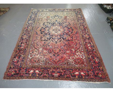 Modern Iranian carpet overall on a salmon ground with central medallion and geometric floral and foliate designs.  337x236cm 