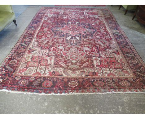 Large Iranian carpet on a red on blue ground overall with stylised flowers and foliage and central medallion.  376x263cm appr