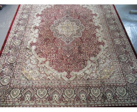 Large modern Kashmiri carpet on a red and cream ground with central floral medallion, overall with geometric floral and folia