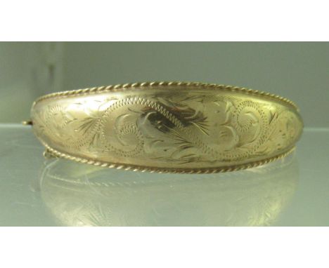 A 9ct gold hinged and engraved bangle.  Approx weight 15.7 grams. (B.P. 21% + VAT) 