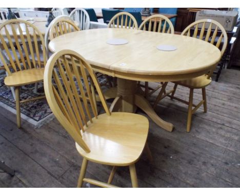 A light beech oval single pillar extending dining table with fold away centre leaf together with six matching slat back Winds