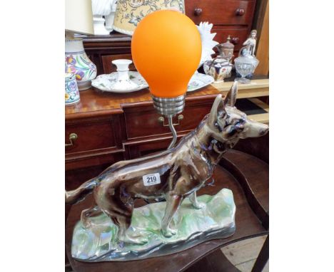 A metal table lamp with orange shade and an Alsatian dog ornament 