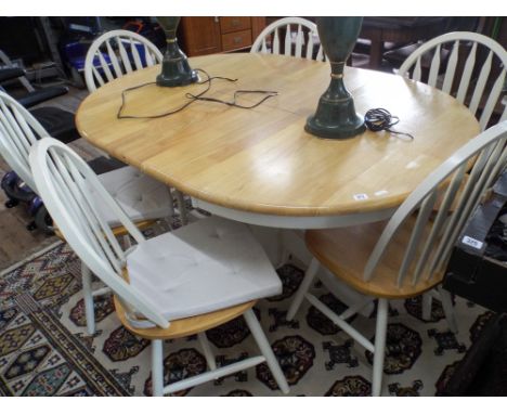A modern oval light oak and white extending dining table with six matching Windsor style chairs 