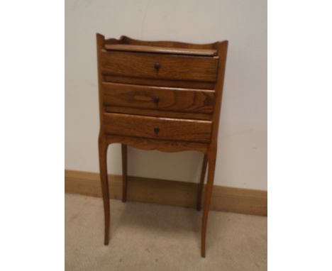 A French light oak three drawer bedside cabinet on cabriole style legs 