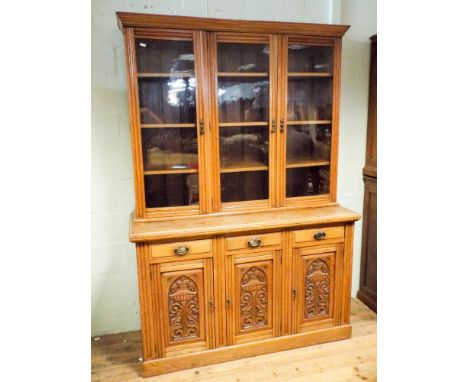 Edwardian light oak three door glazed bookcase standing on sideboard style base with three drawers and cupboards, the cupboar