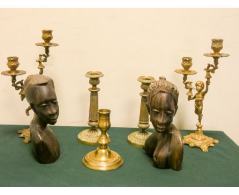 A pair of two branch brass candelabra, pair of candlesticks, two native carved busts and one other candlestick 