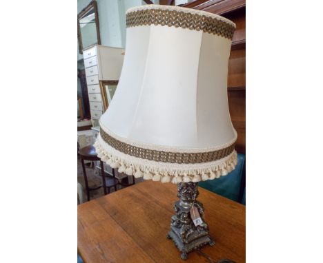 An Italian style decorative metal table lamp, decorated with cherubs, together with a cream shade 