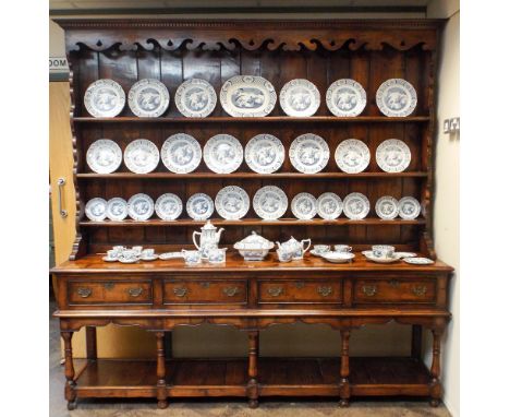 A Georgian style oak and mahogany cross banded Welsh style dresser with closed shelf back, four drawers and plate rack under 