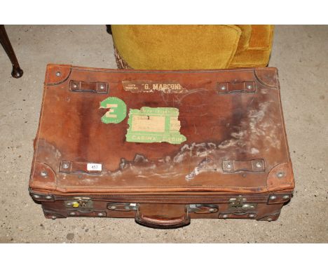 A vintage leather suitcase with various labels