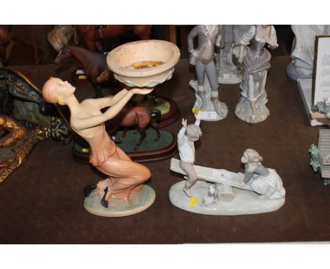 A Nao figure group depicting a girl and boy on a seesaw together with an Art Deco style figure