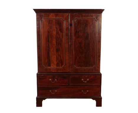 A LATE GEORGE III MAHOGANY LINEN PRESS 18th/19th century, the dentil moulded cornice above panelled doors, opening to a shelv