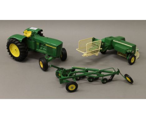 A die cast John Deere tractor, bailer and plough. The tractor 27 cm long.