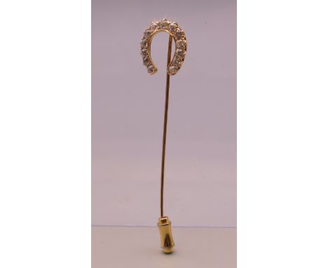 An unmarked gold diamond set horseshoe form stick pin. 6.5 cm long. 2.3 grammes total weight.