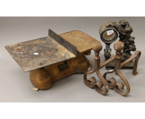 A set of scales, a pair of fire dogs and a clock. 