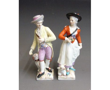 A pair of Berlin figures of a shepherd and shepherdess, she with a lamb and he with a dog at their feet standing on square ro