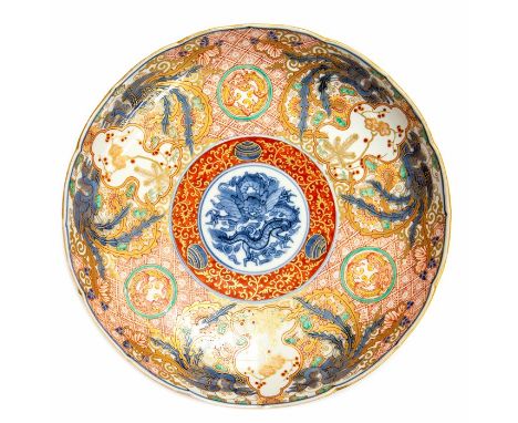 A Chinese famille rose low dish, the central blue and white roundel with a dragon, iron red and gilt scroll borders with cher