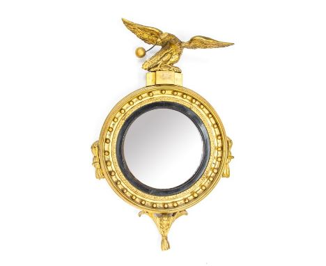 A Regency design gilt wood wall convex looking glass, 19th Century, surmounted with an eagle holding a ball and chain in its 