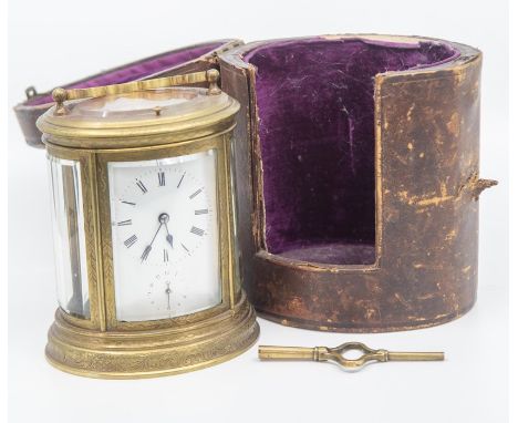 An oval carriage clock, with case and key, the glass&nbsp;to the clock bevelled, the metal surround is engraved.