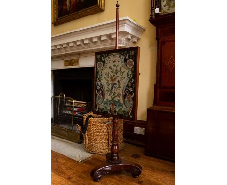A Victorian pole screen, the panel with woolwork design, raised on a turned column, standing on a triform base, with scrolled