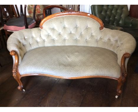 A mid Victorian walnut deep button backed settee, carved crest rail, scrolled arm supports, cabriole legs with white porcelai